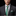 Man wearing a gray suit with a green patterned tie and matching pocket square on a black background