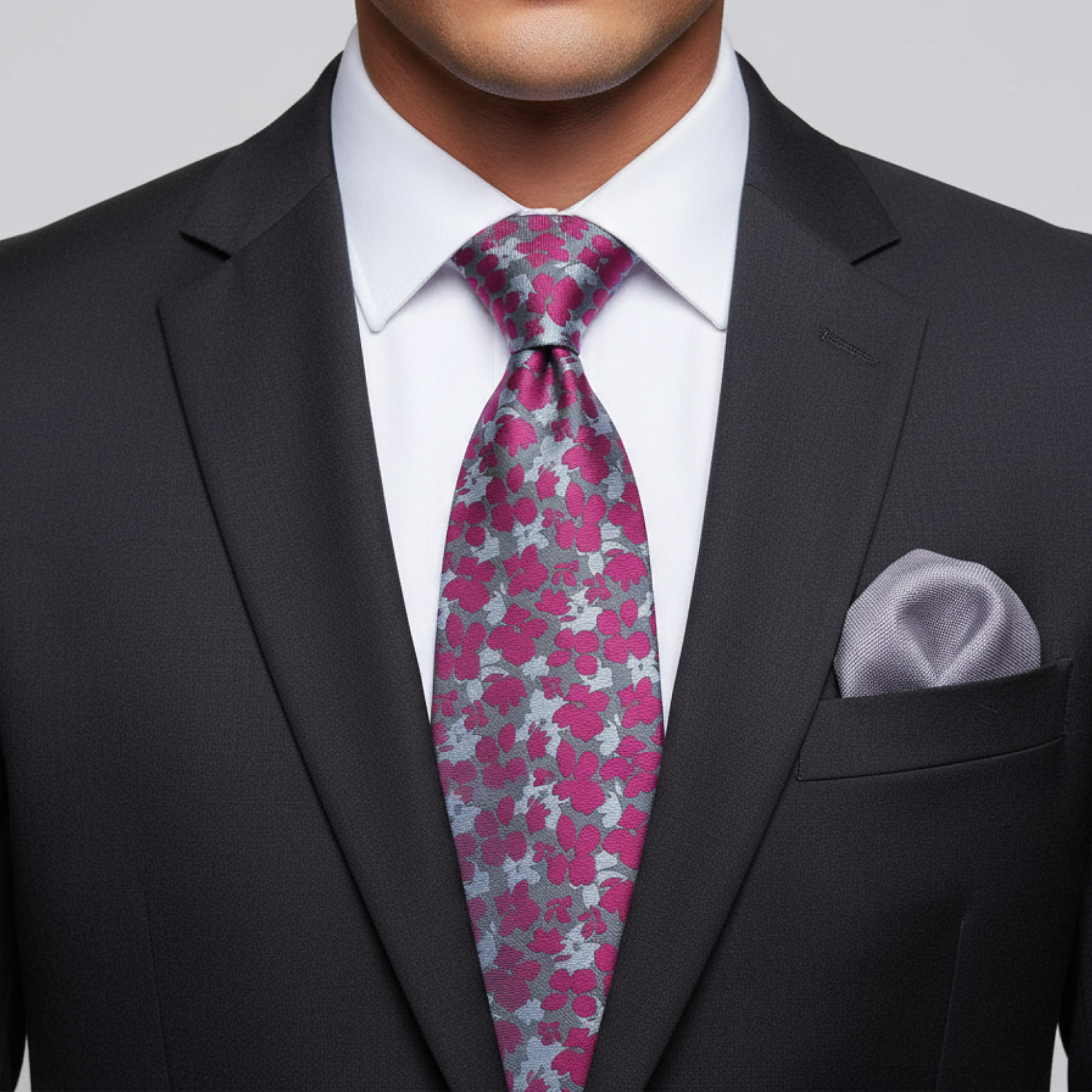 Man wearing a black suit with a pink and gray floral tie and matching pocket square.