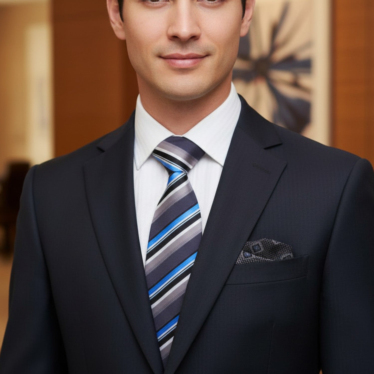 Man wearing a dark suit with a striped tie in an indoor setting
