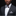 Man wearing a black suit with a white shirt, patterned bow tie, and pocket square against a dark background.