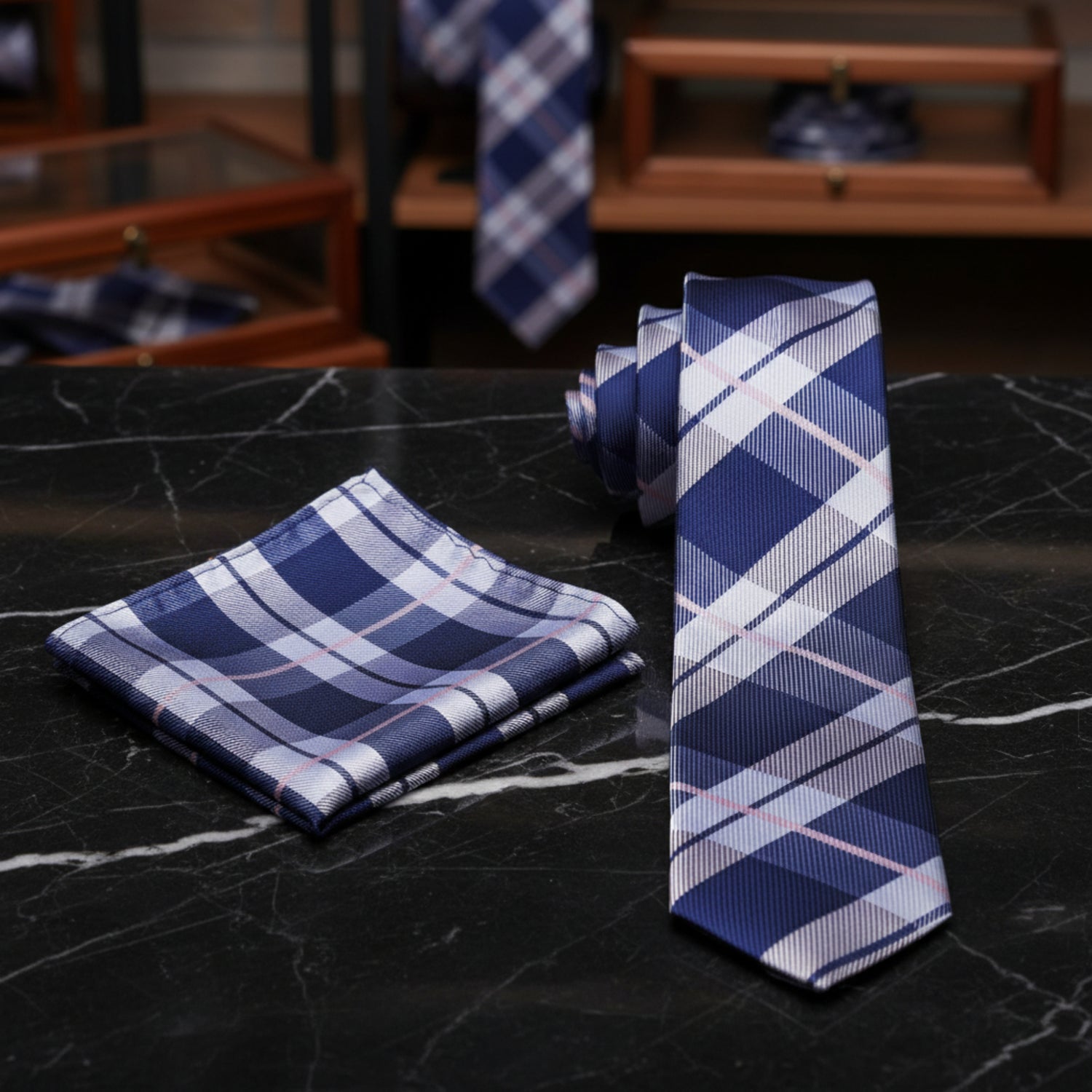 A men's necktie and matching pocket square set in a blue, white, and light pink plaid pattern, displayed on a clean white background.