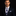 Man wearing a dark suit with a Grey and Dark Blue Plaid Tie against a black background