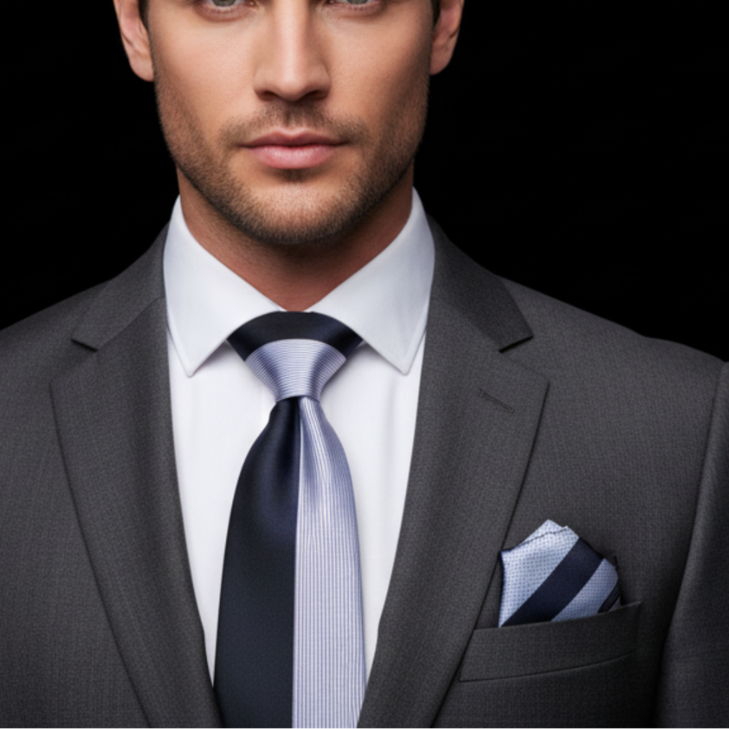 Man wearing a gray suit with a blue tie and pocket square against a black background