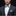 Man wearing a dark suit with a colorful bow tie and pocket square on a black background
