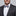 Man wearing a gray suit with a patterned bow tie and pocket square on a gray background