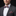 Man wearing a gray suit with a colorful bow tie and pocket square against a black background