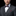 Man wearing a gray suit with a plaid bow tie and pocket square on a black background