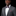 Man wearing a gray suit with a red and grey bow tie and pocket square on a black background