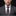 Man wearing a gray suit with a patterned tie and pocket square on a black background