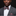 Man wearing a gray suit with a patterned bow tie and pocket square against a black background