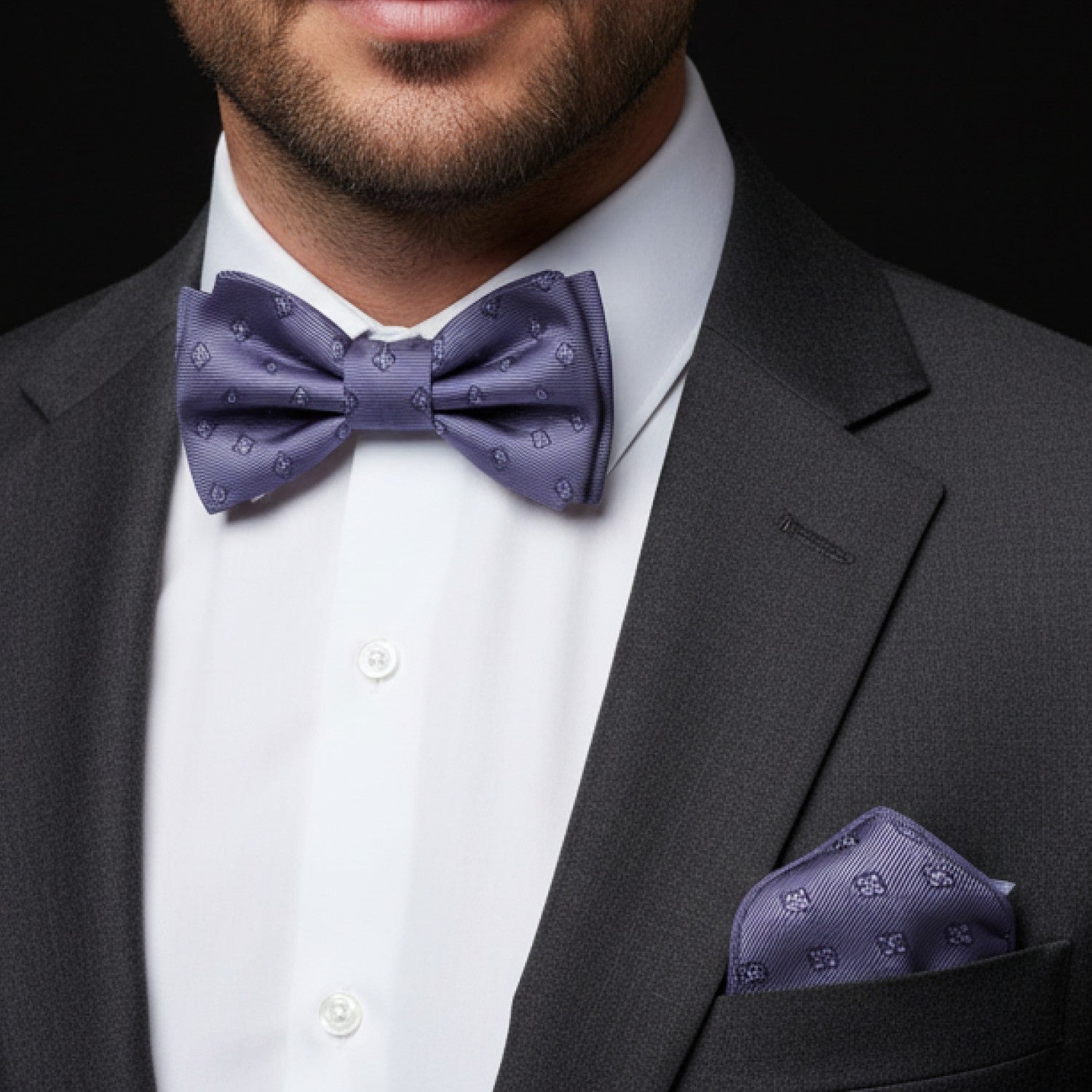 Man wearing a gray suit with a white shirt and grey bow tie and pocket square.