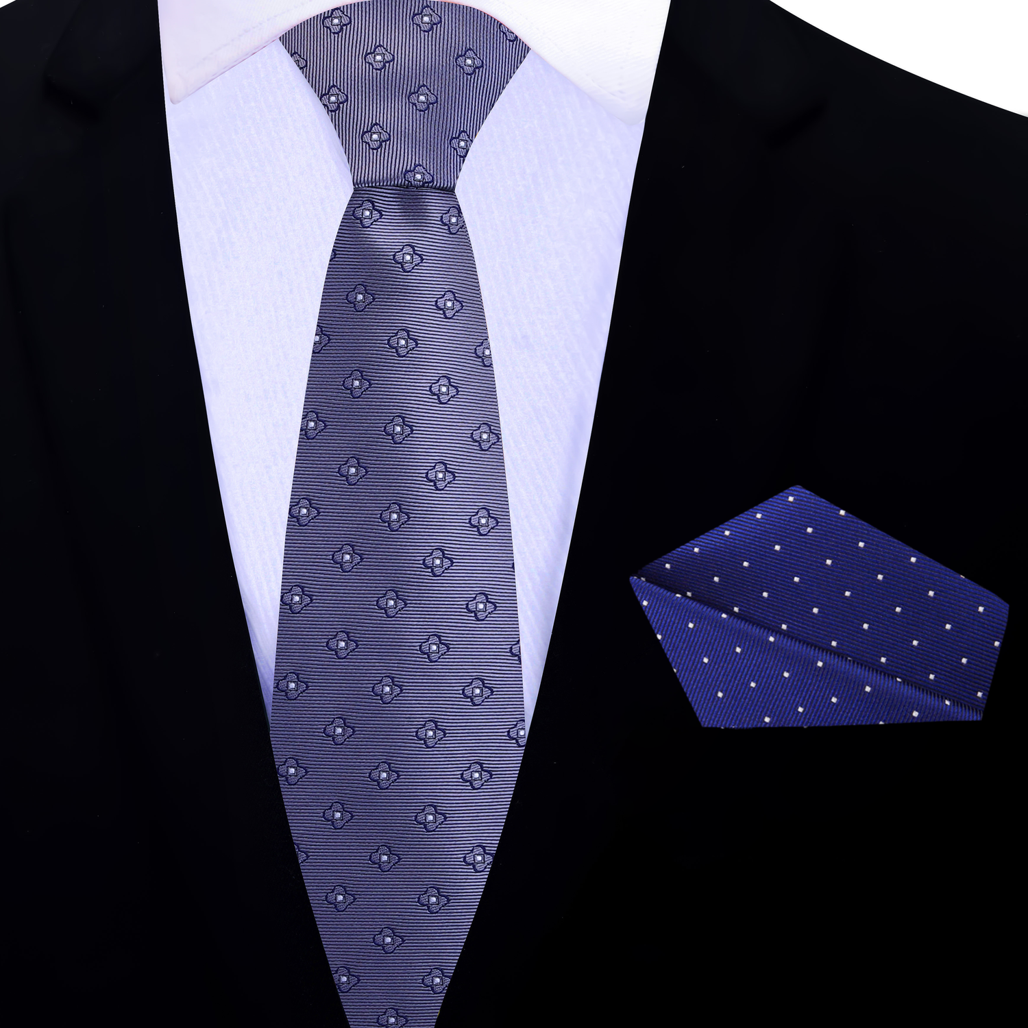 Grey floral thin tie and accenting blue with white dots pocket square on a black suit jacket.