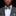 Man wearing a gray suit with a checkered bow tie and pocket square against a black background