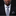Man wearing a black suit with a patterned tie and pocket square on a dark background