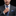 Man adjusting his blue plaid tie against a black background