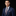 Man wearing a blue suit with a red tie against a black background