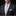 Man wearing a black suit with a white shirt, gray tie, and pocket square on a black background