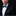 Man wearing a black suit with a blue bow tie and pocket square against a black background