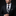 Man wearing a black suit with a decorative tie against a dark background