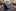 Blue polka dot tie on a marble surface with a blurred background of suits.