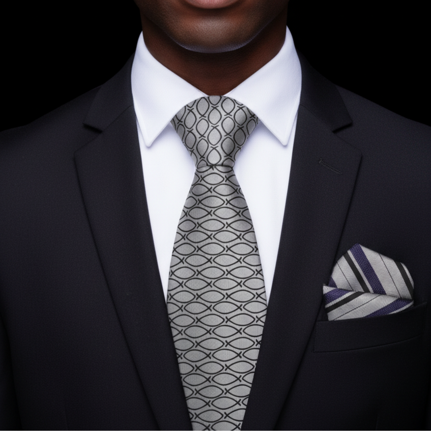 Man wearing a black suit with a patterned tie and pocket square against a dark background