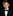 Young boy in a formal black suit with a blue bow tie on a black background