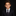 A young boy with styled brown hair wearing a dark navy suit, white dress shirt, and a dark patterned tie, photographed against a solid black background.