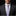 Man wearing a dark suit with a light purple striped tie against a black background