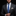 Man wearing a dark suit with a blue tie and patterned pocket square on a black background