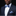 Man wearing a navy suit with a blue checkered bow tie and pocket square on a black background