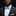 Man wearing a black suit with a white shirt and blue bow tie on a black background