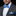 Man wearing a gray suit with a blue polka dot bow tie and pocket square on a black background