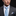 Man wearing a gray suit with a light blue tie and pocket square on a black background