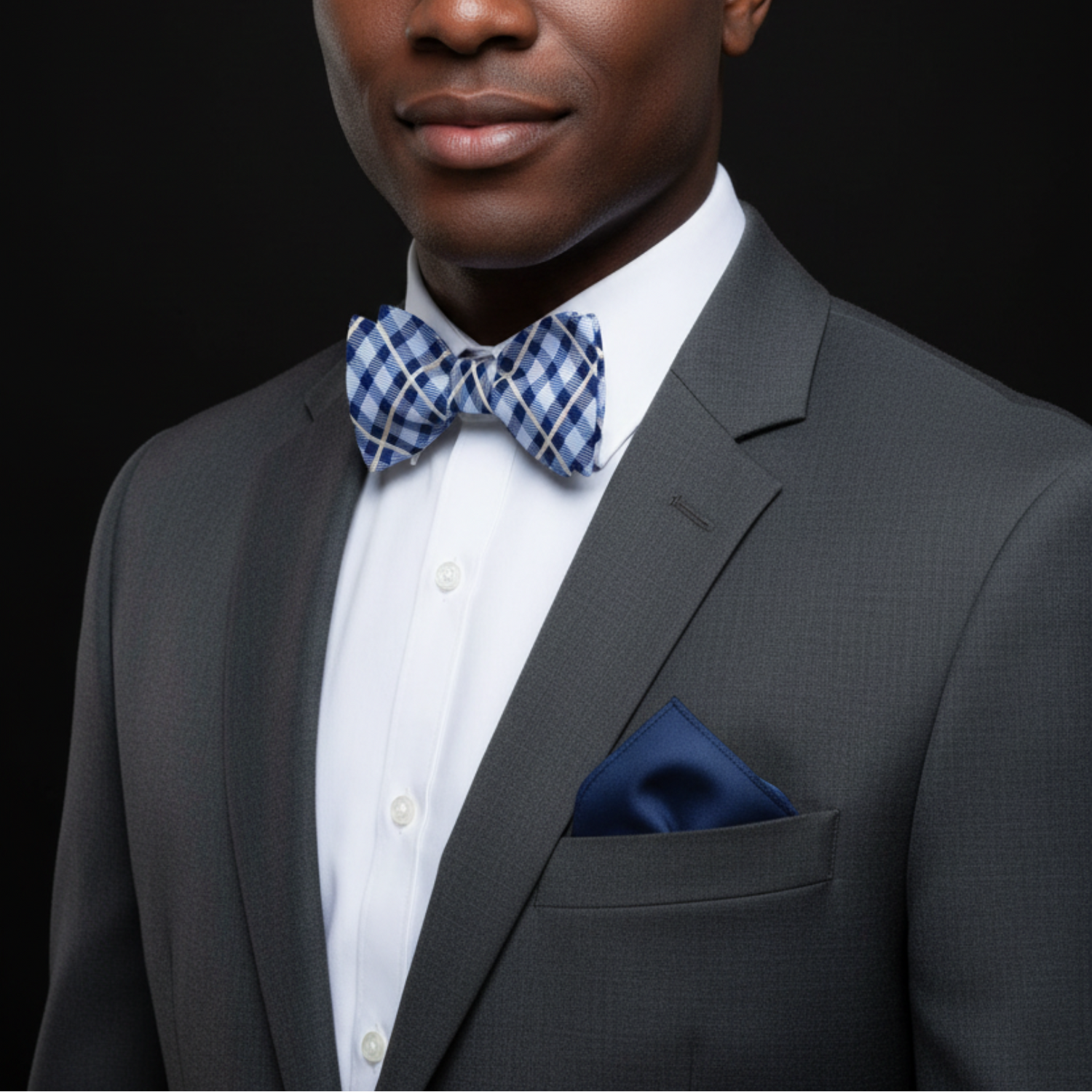 A plaid patterned bow tie in shades of blue and yellow, displayed on a white background with a solid blue pocket square.
