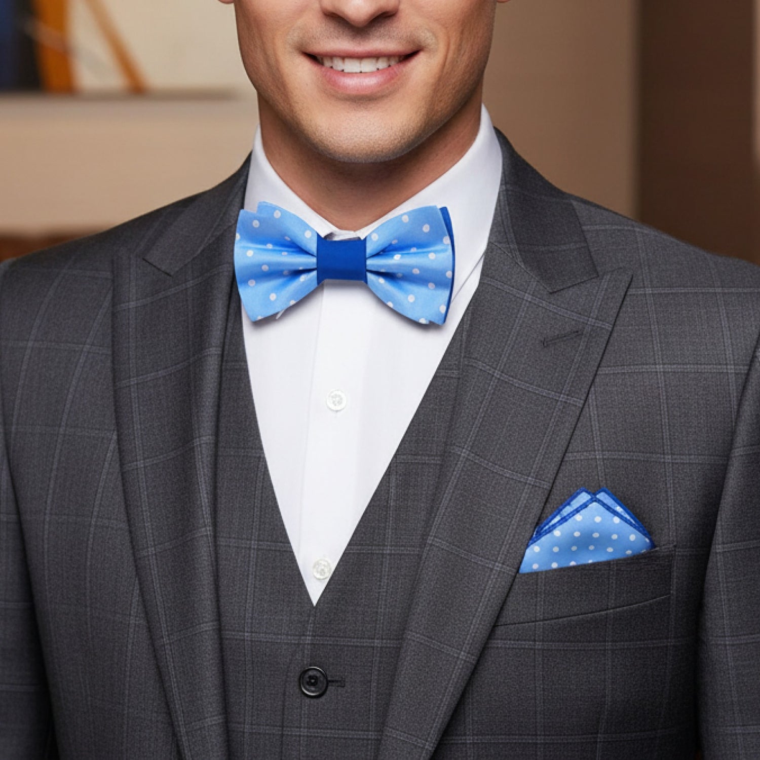 Man wearing a gray suit with a blue bow tie and pocket square.