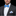 Man wearing a black suit with a white shirt, blue bow tie, and matching pocket square on a black background.