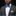 Man wearing a gray suit with a blue and green patterned bow tie and gold pocket square on a black background