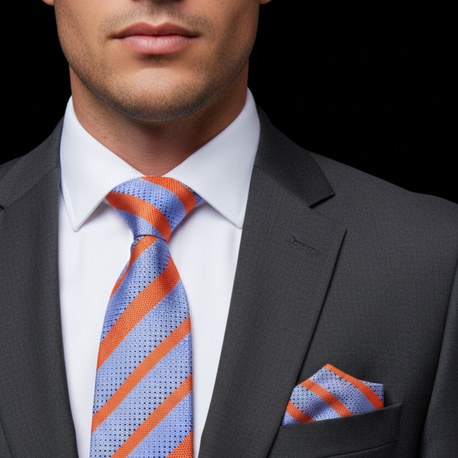 Man wearing a gray suit with a blue and orange striped tie and pocket square.