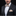 Man wearing a black tuxedo with a patterned bow tie and pocket square on a black background