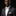 Man wearing a black suit with a beige bow tie and pocket square on a black background