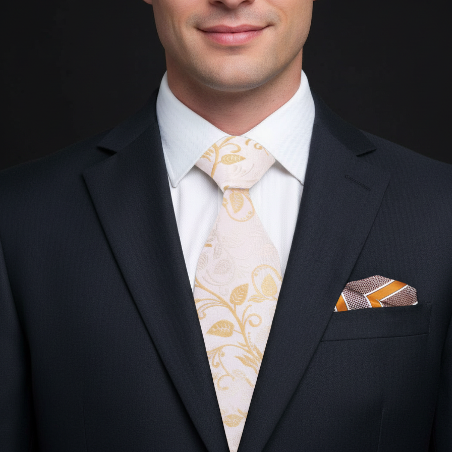 Man wearing a dark suit with a white shirt, patterned tie, and pocket square on a black background