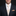 Man wearing a dark suit with a white shirt, patterned tie, and pocket square on a black background