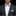 Man wearing a black suit with a beige bow tie and pocket square on a black background