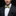 Man wearing a black suit with a white shirt and gold bow tie on a black background