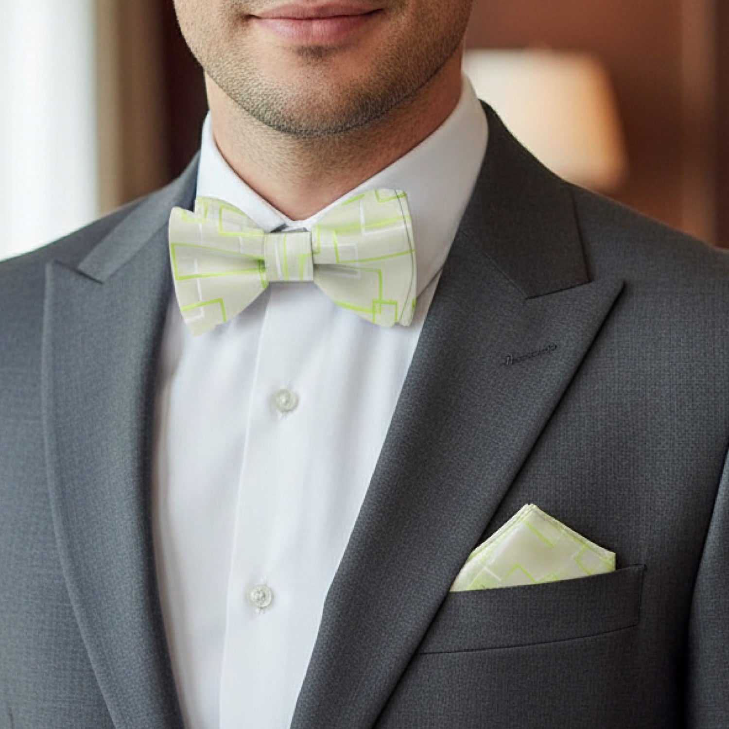 Man wearing a gray suit with a white shirt, green bow tie, and matching pocket square.