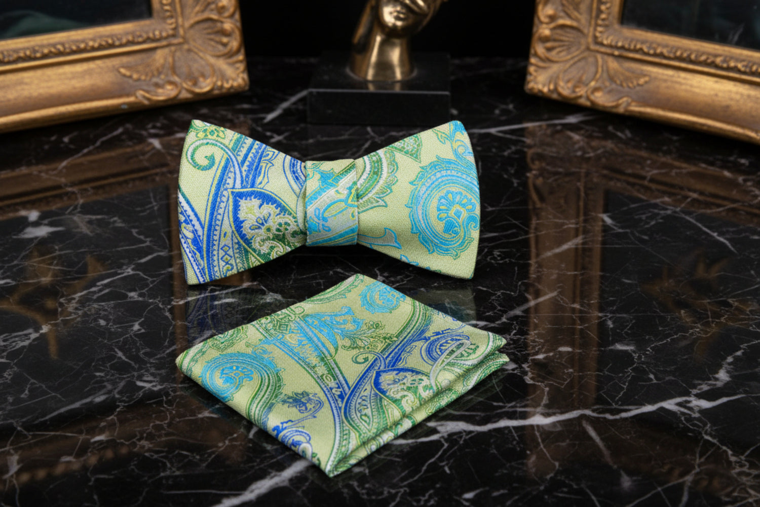 Green and blue paisley bow tie and pocket square set on a black marble