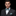Man wearing a black suit with a green and white bow tie and pocket square on a black background