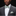 Man wearing a gray suit with a green and white striped bow tie and pocket square against a black background