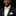 Man wearing a black tuxedo with a green and white bow tie and pocket square against a dark background
