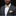 Man wearing a gray suit with a yellow and gray patterned bow tie and pocket square against a black background